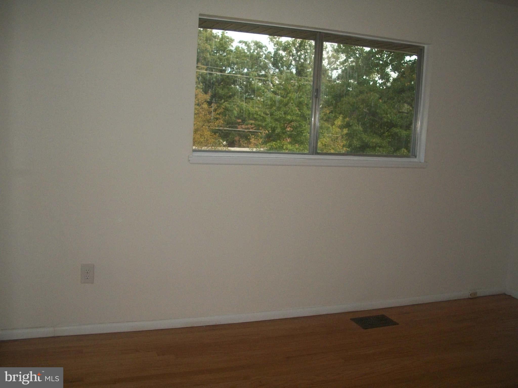 5634 Westgate Road Lanham, MD 20706 - Photo 7 of 12 a view of an empty room with wooden floor and a window