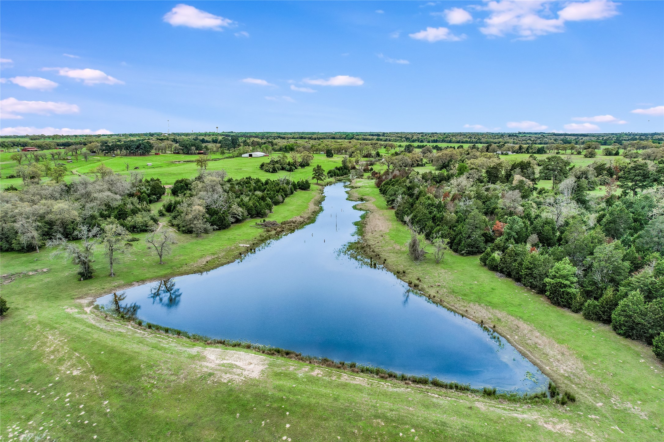 363 Paint Creek S Road, Unit A Paige, TX 78659 - Photo 19 of 28 Vast green acreage punctuated by a meandering pond, offering a serene, private landscape.