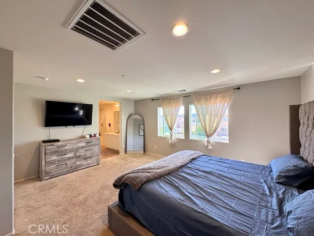 a bedroom with a bed a television and a large window