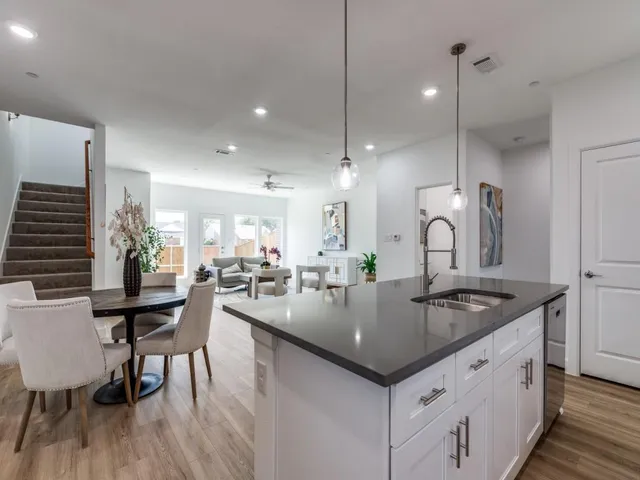 a kitchen with a dining table chairs sink and wooden floor