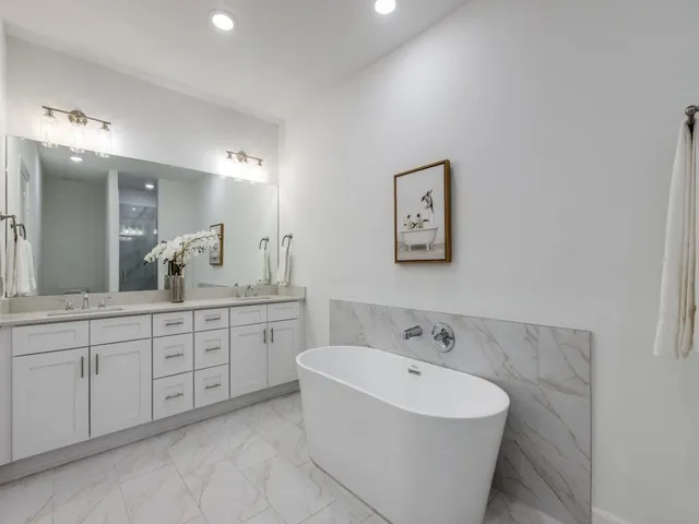 a spacious bathroom with a double vanity sink mirror and bathtub