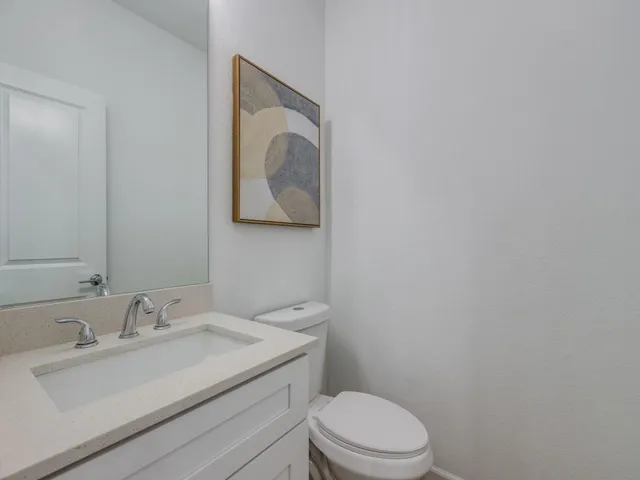 a bathroom with a toilet sink vanity and mirror