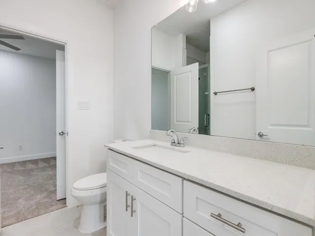 a bathroom with a granite countertop sink a toilet and a mirror