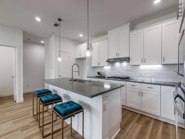 a kitchen with stainless steel appliances granite countertop a sink a stove and a wooden floors