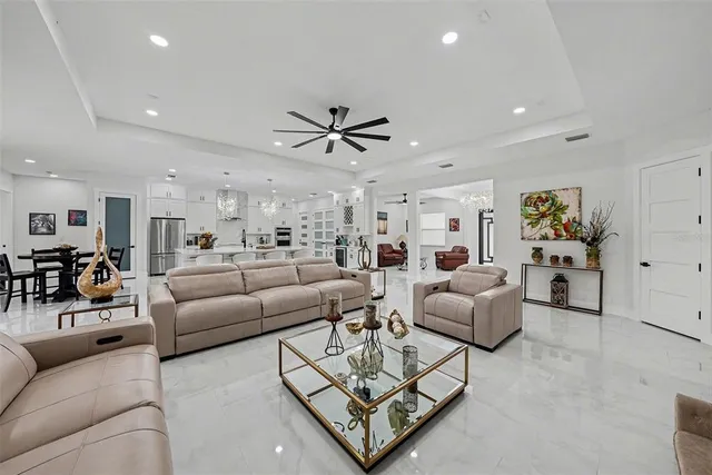 a living room with furniture kitchen view and a chandelier