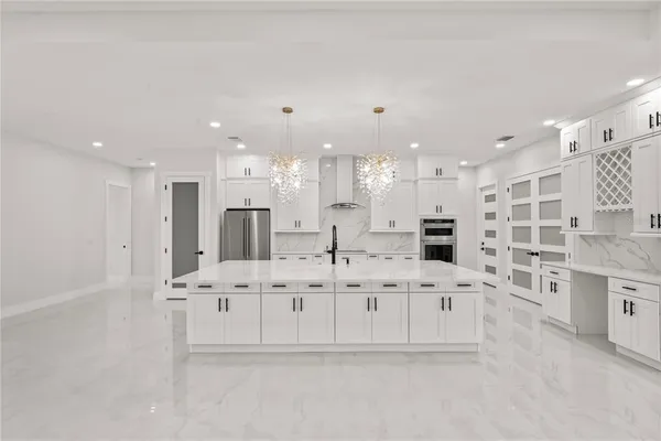 a large white kitchen with kitchen island granite countertop a sink and cabinets