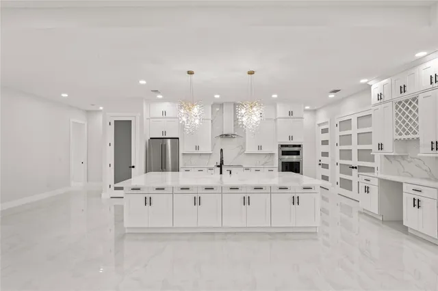 a large white kitchen with kitchen island granite countertop a sink and cabinets