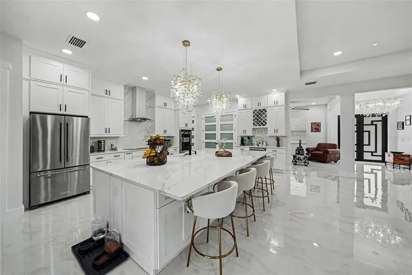 a kitchen with stainless steel appliances kitchen island granite countertop a table chairs refrigerator and microwave