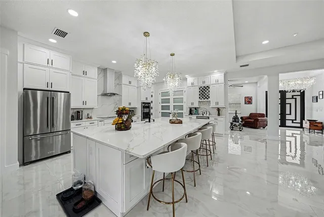 a kitchen with stainless steel appliances kitchen island granite countertop a table chairs refrigerator and microwave