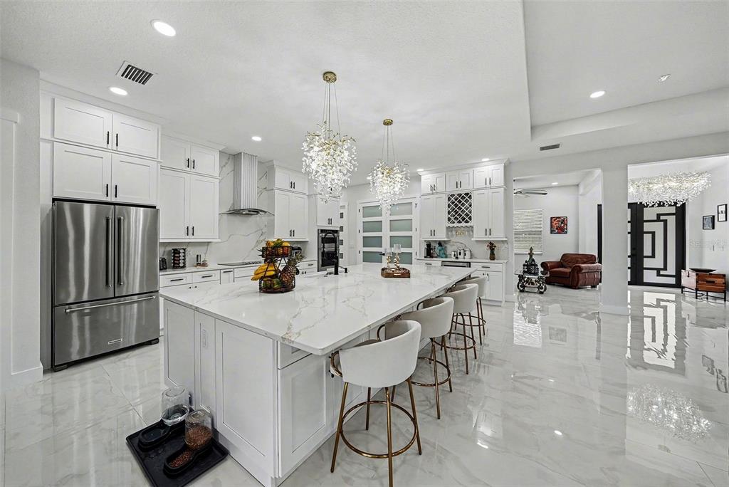 14060 Sydney Road Dover, FL 33527 - Photo 21 of 49 a kitchen with stainless steel appliances kitchen island granite countertop a table chairs refrigerator and microwave