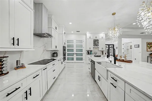 a large kitchen with granite countertop a sink dishwasher a stove and a dining table with wooden floor