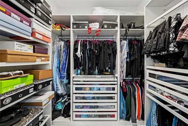 a view of walk in closet with clothes and shoes