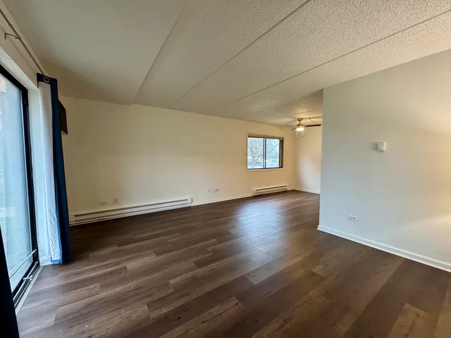 an empty room with wooden floor and windows with curtains