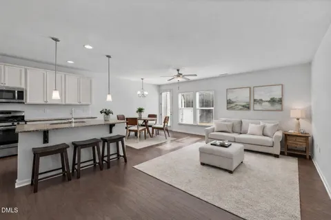 a living room with furniture white walls and kitchen view