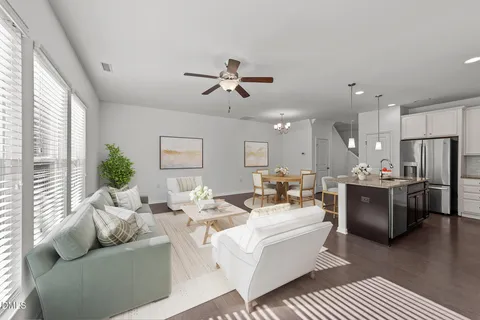 a living room with furniture kitchen area and a large window