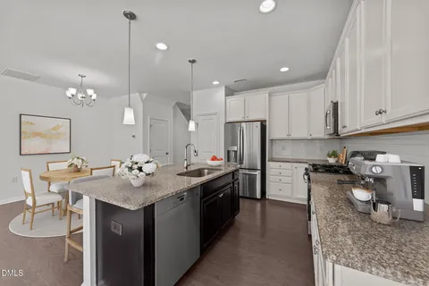 a kitchen with stainless steel appliances granite countertop a sink a stove a refrigerator cabinets and chairs