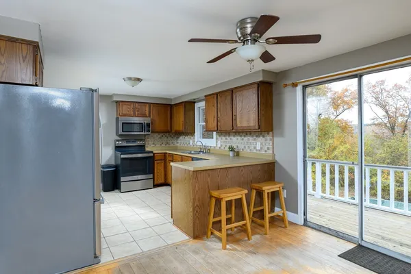 a kitchen with stainless steel appliances granite countertop a refrigerator a sink dishwasher a stove and a dining table with wooden floors
