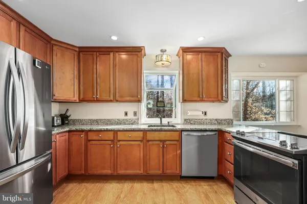 a kitchen with stainless steel appliances kitchen island granite countertop a dining table chairs and a refrigerator