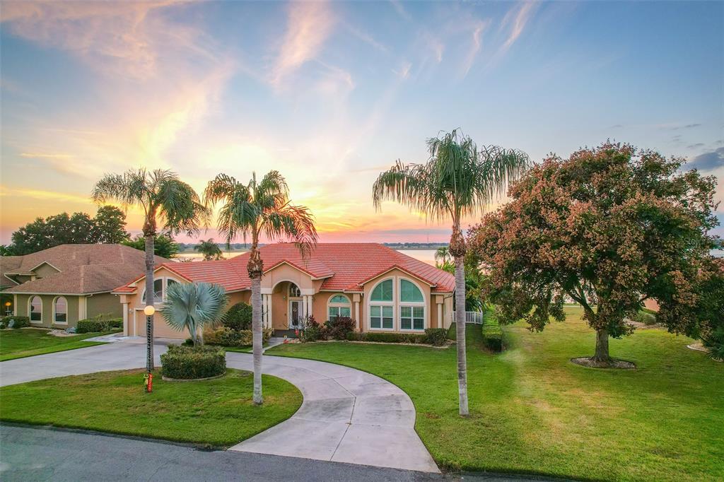 116 Raintree Court Auburndale, FL 33823 - Photo 3 of 45 a view of a white house with a big yard and palm trees
