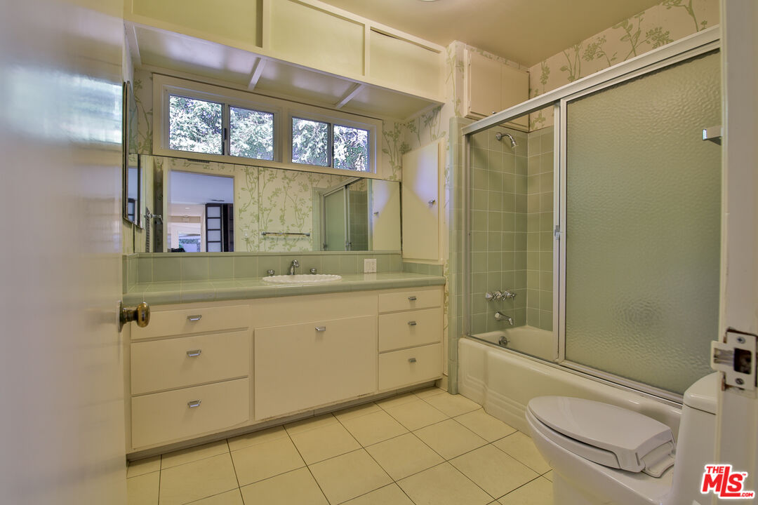 1749 Mandeville Lane Los Angeles, CA 90049 - Photo 25 of 38 a bathroom with a granite countertop sink toilet a mirror a vanity and bathtub