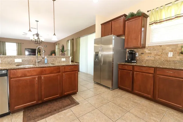a kitchen with stainless steel appliances granite countertop a sink a refrigerator and a wooden cabinets