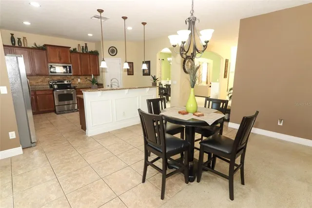 a kitchen with stainless steel appliances kitchen island granite countertop a table chairs and a refrigerator