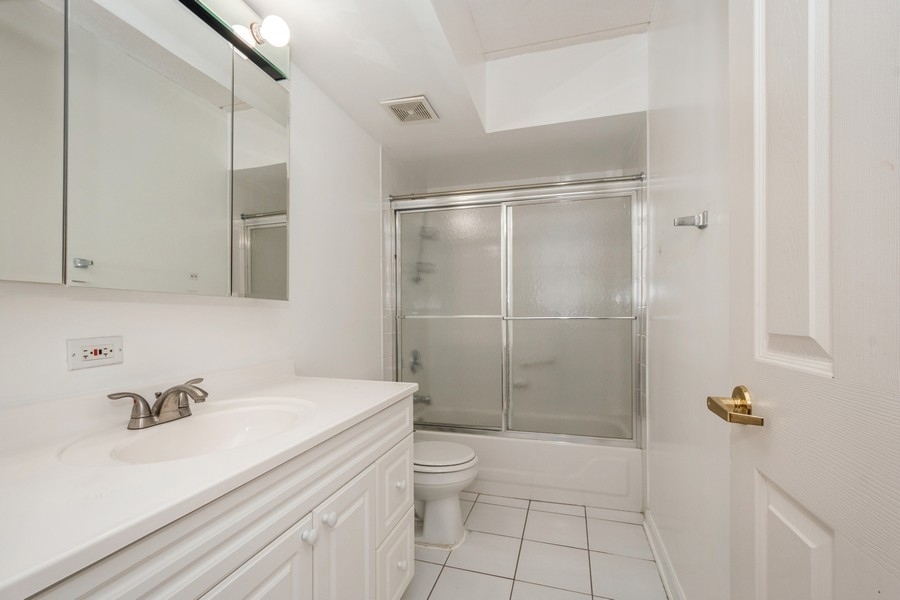 9220 East Prairie Road, Unit 303 Evanston, IL 60203 - Photo 11 of 13 a bathroom with a shower sink vanity and toilet