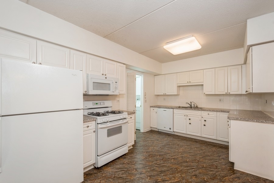 9220 East Prairie Road, Unit 303 Evanston, IL 60203 - Photo 5 of 13 a kitchen with granite countertop white cabinets and white appliances