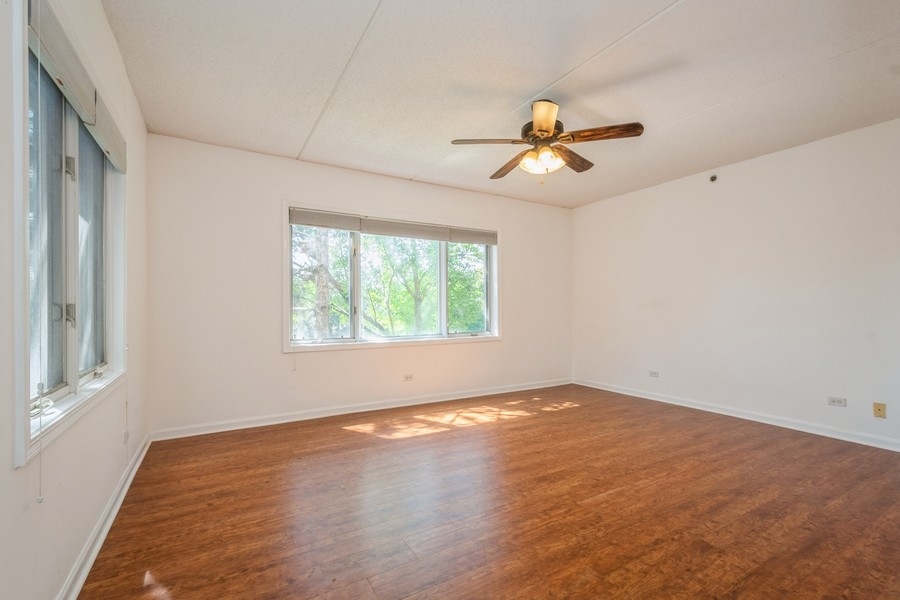 9220 East Prairie Road, Unit 303 Evanston, IL 60203 - Photo 6 of 13 an empty room with wooden floor ceiling fan and windows