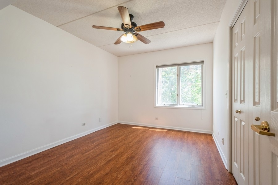 9220 East Prairie Road, Unit 303 Evanston, IL 60203 - Photo 9 of 13 an empty room with wooden floor fan and windows