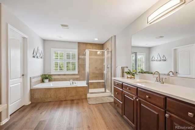 a spacious bathroom with double vanity a large mirror a bathtub and a shower