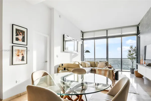 a kitchen with stainless steel appliances kitchen island a stove a sink a refrigerator and chairs with wooden floor
