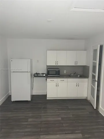 a kitchen with granite countertop white cabinets and refrigerator