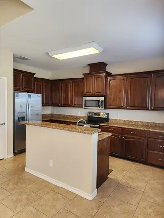a kitchen with stainless steel appliances granite countertop a stove top oven a sink and a refrigerator
