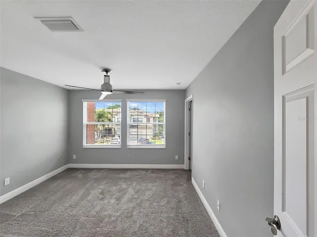 a big room with windows and chandelier fan