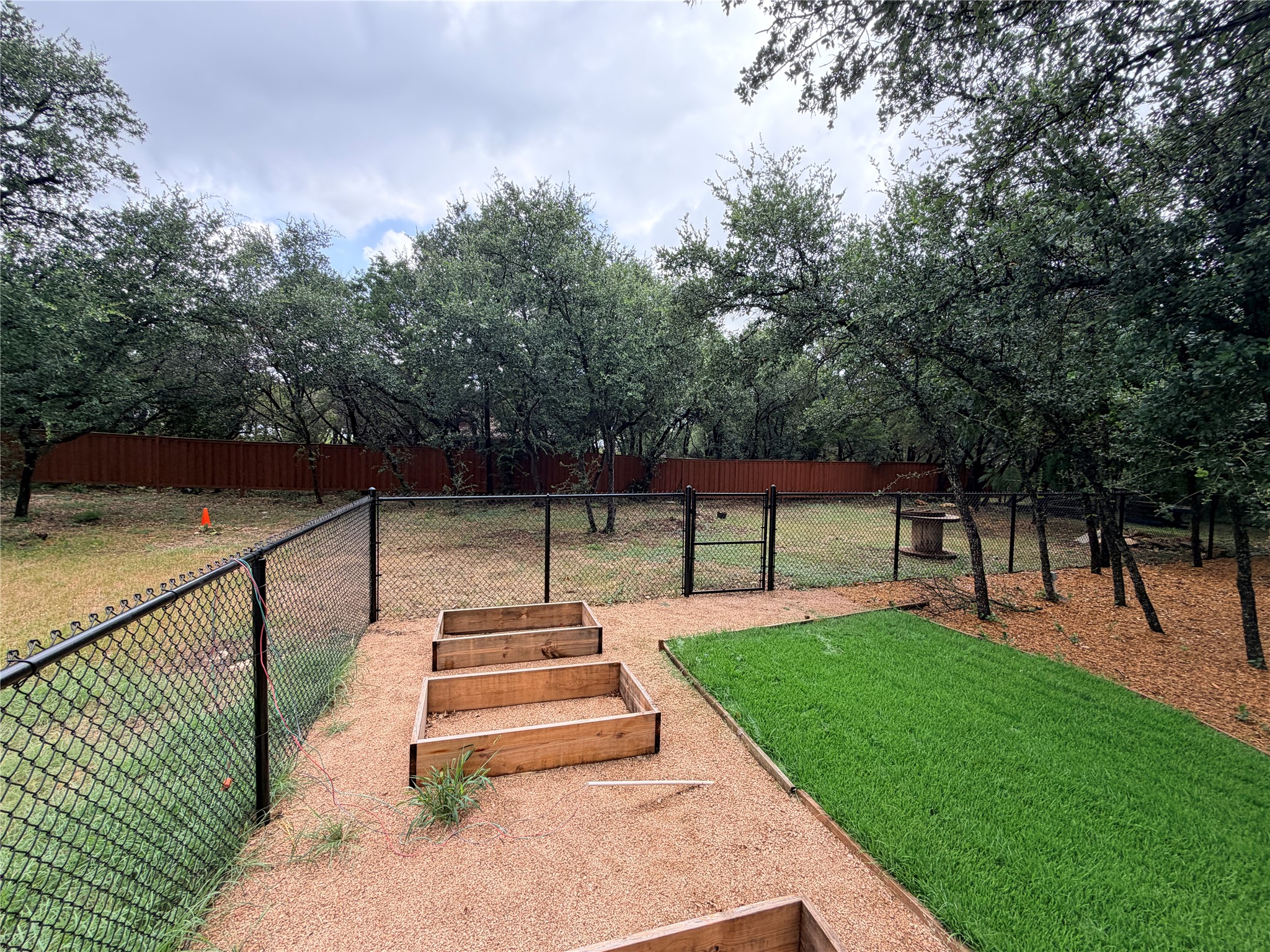 7130 Ranch 2338 Road Georgetown, TX 78633 - Photo 14 of 35 Mature trees frame a fenced backyard complete with established garden beds and green lawns.