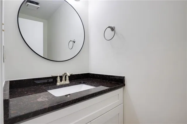 a bathroom with a granite countertop sink and a mirror