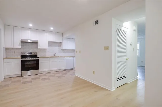 a kitchen with a refrigerator and white cabinets
