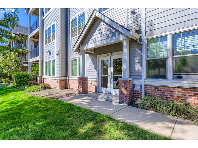 a view of a brick house with many windows next to a yard