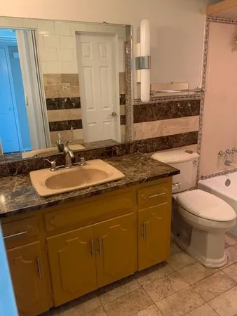 a bathroom with a granite countertop toilet sink and mirror