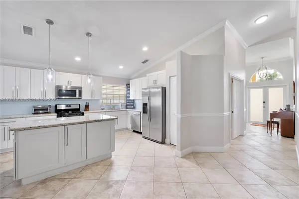 a open kitchen with stainless steel appliances granite countertop a refrigerator and a stove top oven