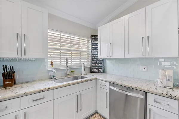 a kitchen with granite countertop a sink white cabinets and a window