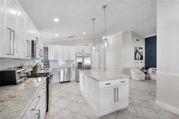 a large white kitchen with stainless steel appliances kitchen island granite countertop a sink and cabinets
