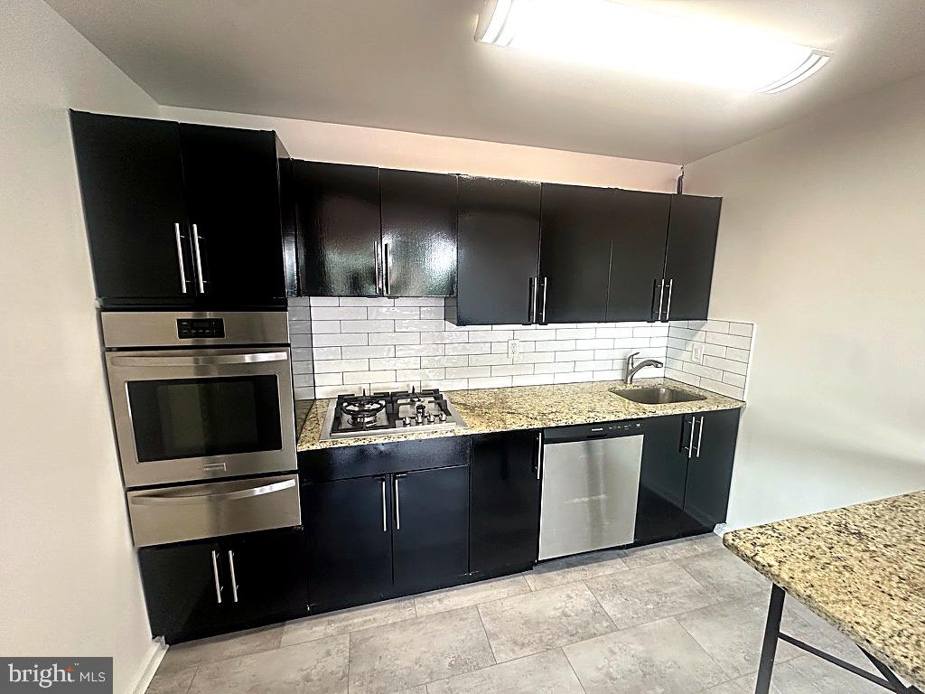 1401 Pennsylvania Avenue, Unit 612 Wilmington, DE 19806 - Photo 11 of 37 a kitchen with stainless steel appliances kitchen island granite countertop a stove a sink and a microwave