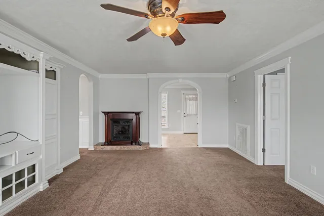 a view of an empty room with chandelier fan and fire place