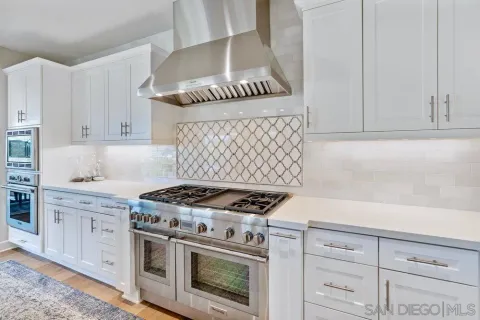 a kitchen with granite countertop a stove and a white cabinets