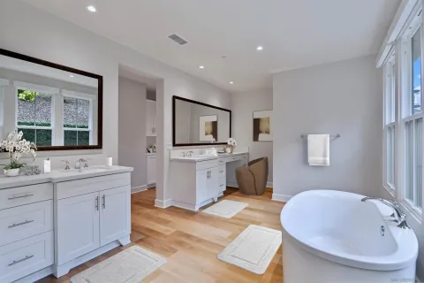 a spacious bathroom with a double vanity sink a mirror and a bathtub