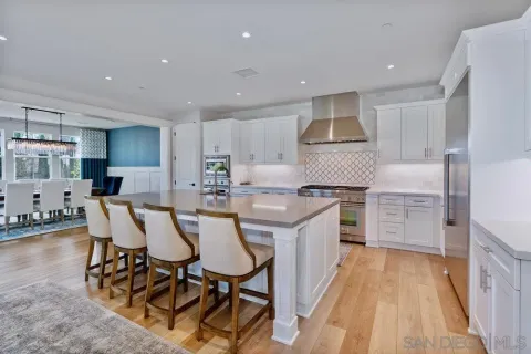 a kitchen with stainless steel appliances kitchen island granite countertop a dining table chairs sink and cabinets