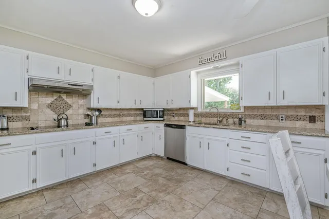 a kitchen with granite countertop white cabinets white appliances with a sink and dishwasher