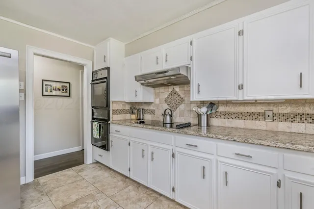 a kitchen with stainless steel appliances granite countertop a sink and a white cabinets